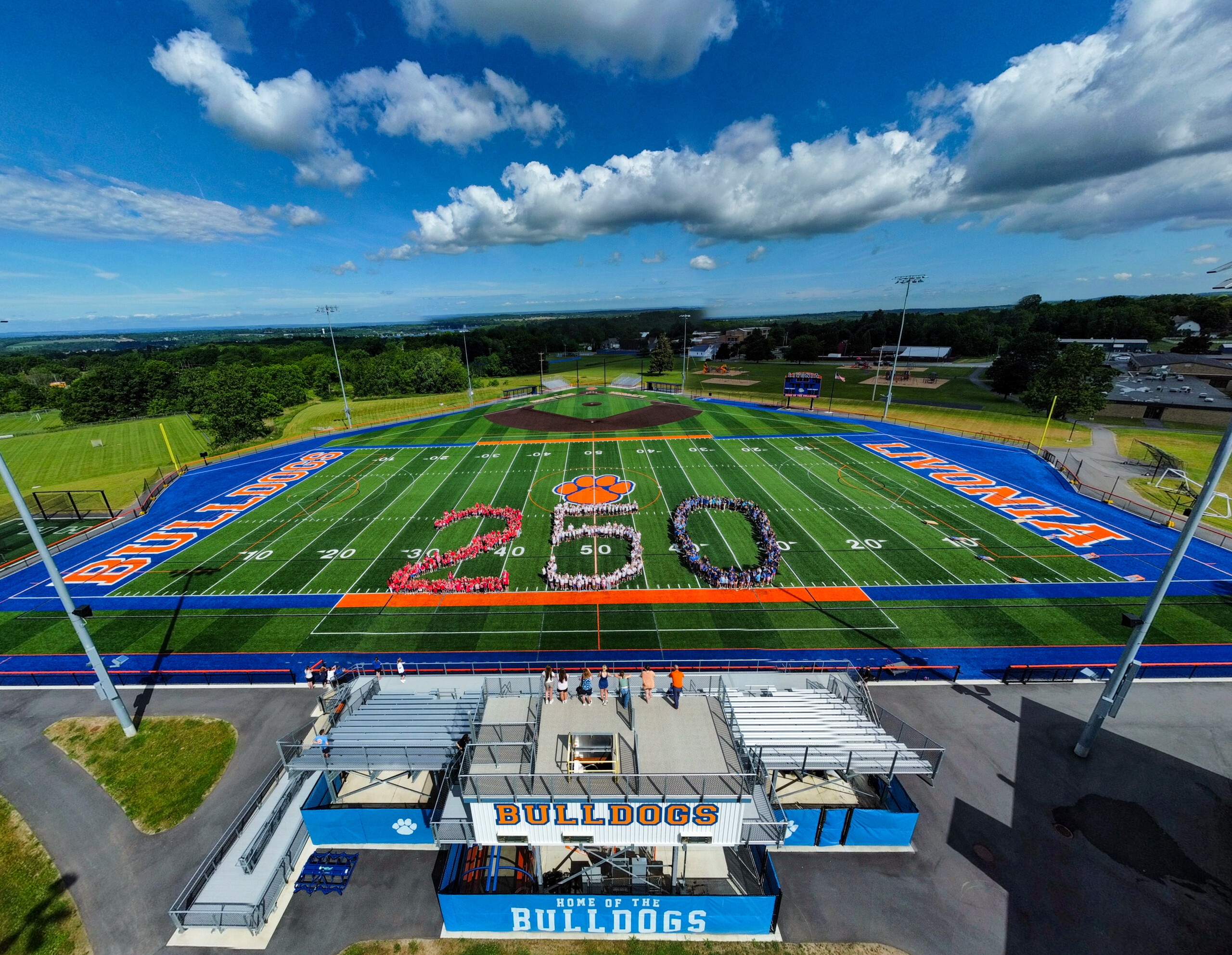 An aerial view of a football field with students forming the number 250 in the center.